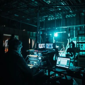 a sound designer sits near a microphone equalizer during a black box production