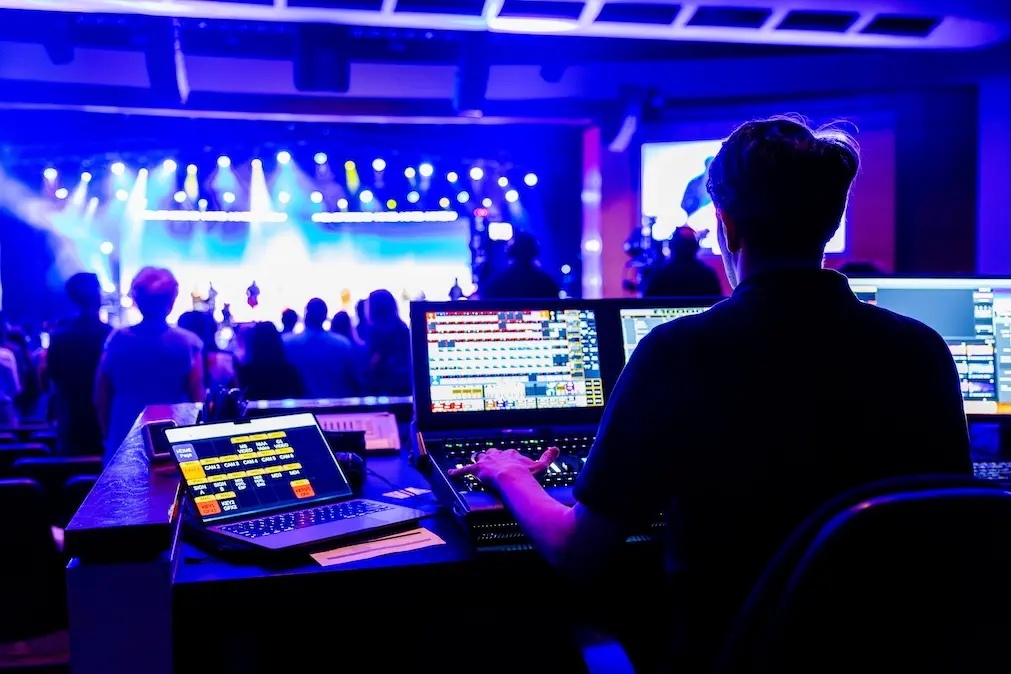 a lighting designer runs a show in front of a lighting console.