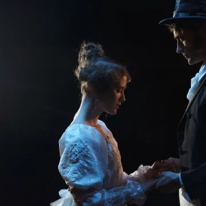 two actors in costume hold hands in a romantic scene