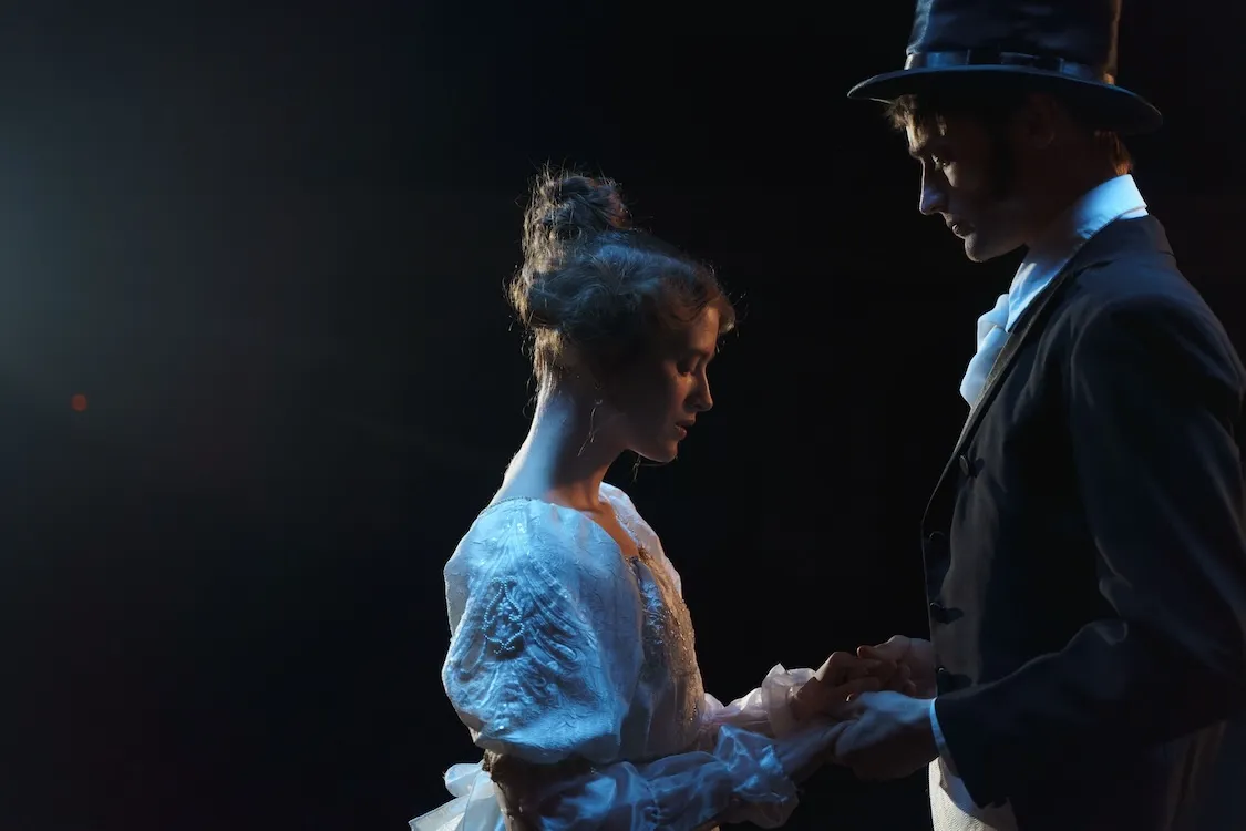 two actors in costume hold hands in a romantic scene
