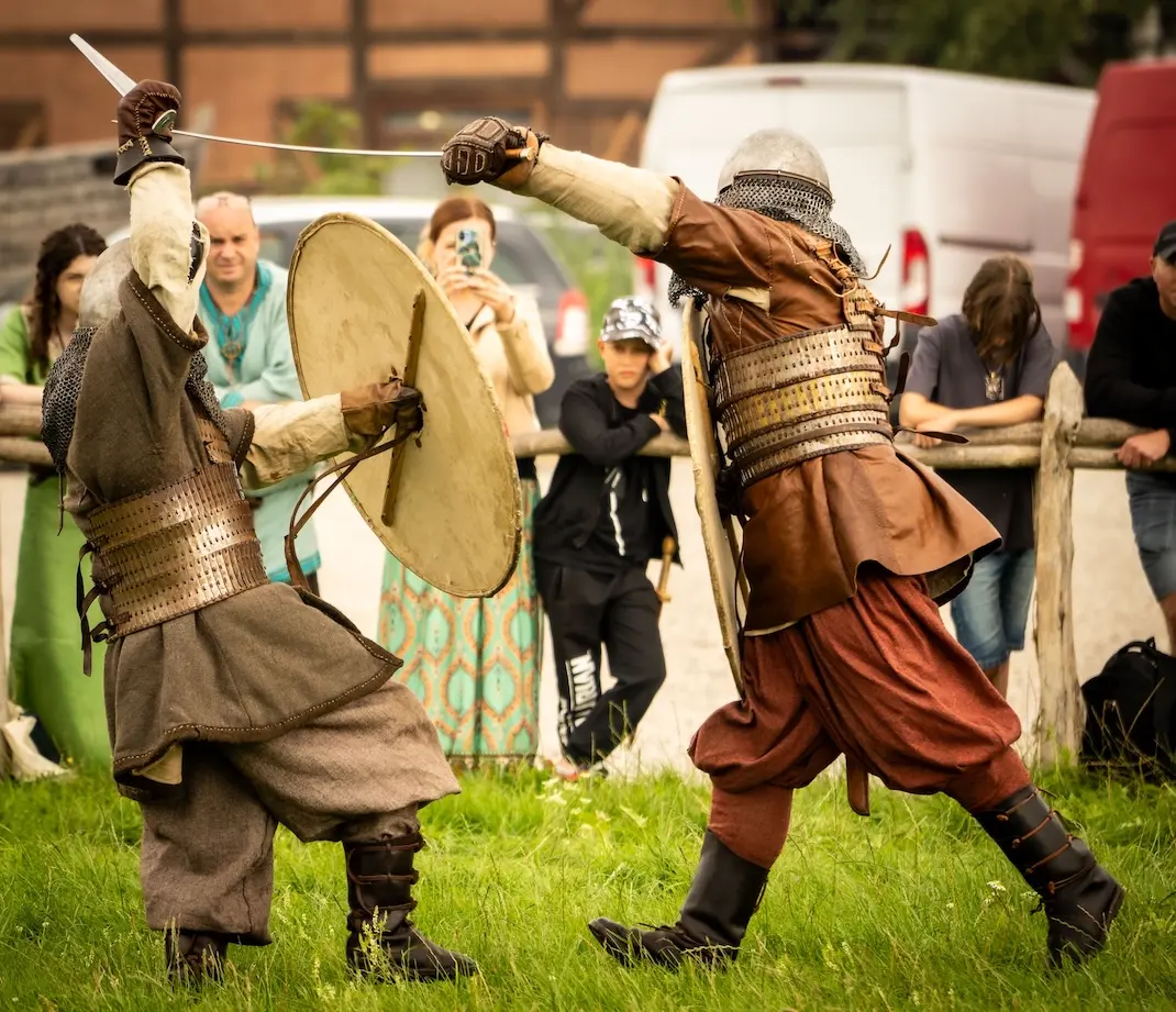 two actors in medieval garb fight in armmor at a rennaisance fair