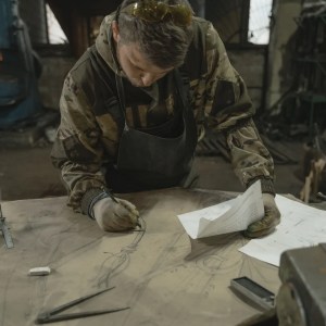 a technical director reviews some plans, leaning over a work bench.