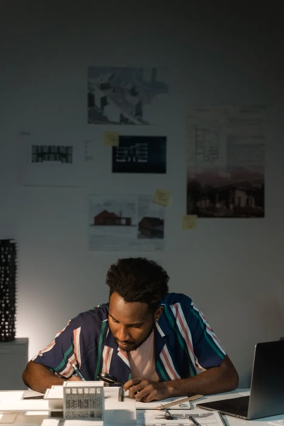 a designer leans over a drafting table working on a model