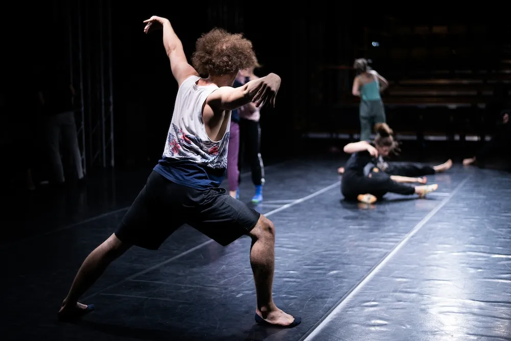 a choreographer demonstrates a pose on a sprung dance floor stage.